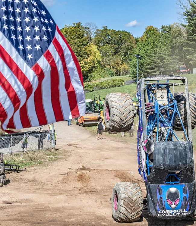 Monster truck flipping over with American flag in the foreground