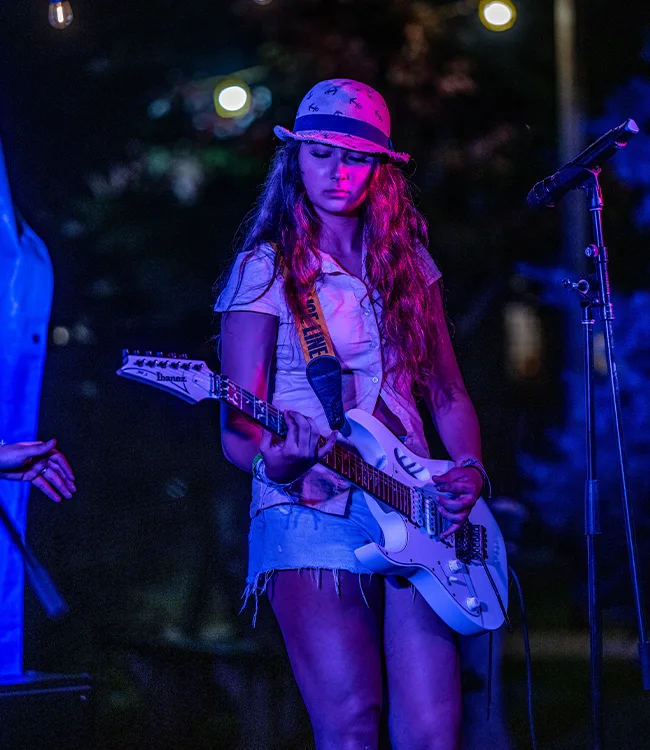 Female guitarist performing with white Ibanez Jem guitar