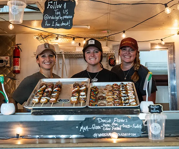 Three women selling donuts at a food stand