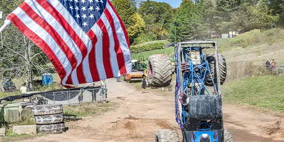 Monster truck flipping over with American flag in the foreground