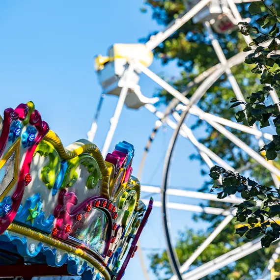 The top of a carousel with a Ferris wheel in the background