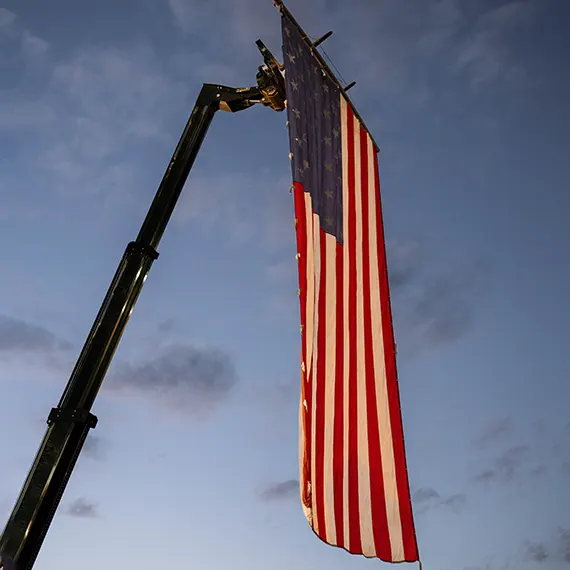Large American flag hanging down from a crane
