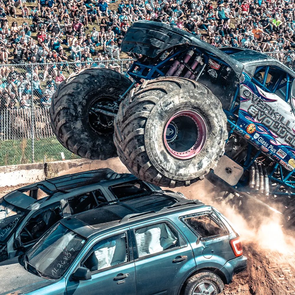 Monster truck driving over two jeeps