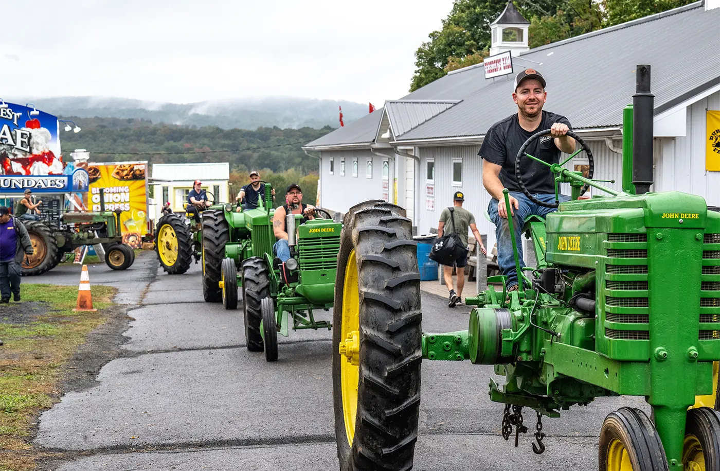 Men driving tractors through the fairground